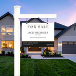 A white real estate 'For Sale' sign on a post in front of a suburban house at dusk, with the name Jack Michaels printed on the sign.