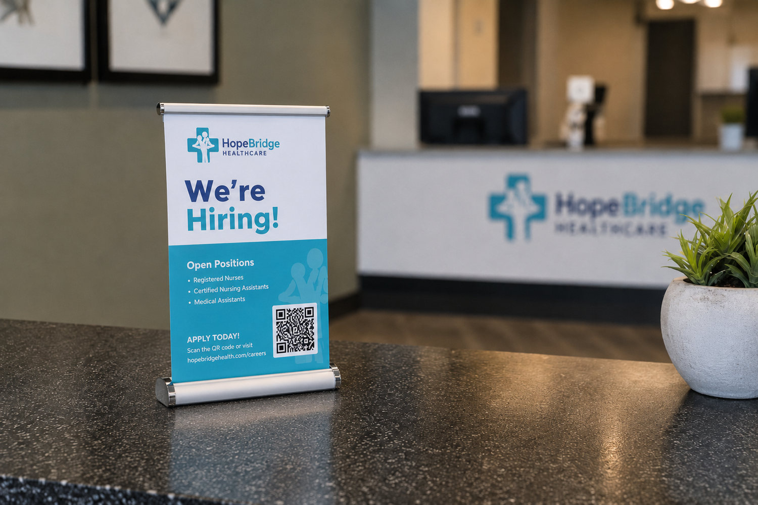 A HopeBridge Healthcare 'We're Hiring!' roll-up sign on a dark countertop in a reception area, with the company logo visible on the counter in the blurred background.